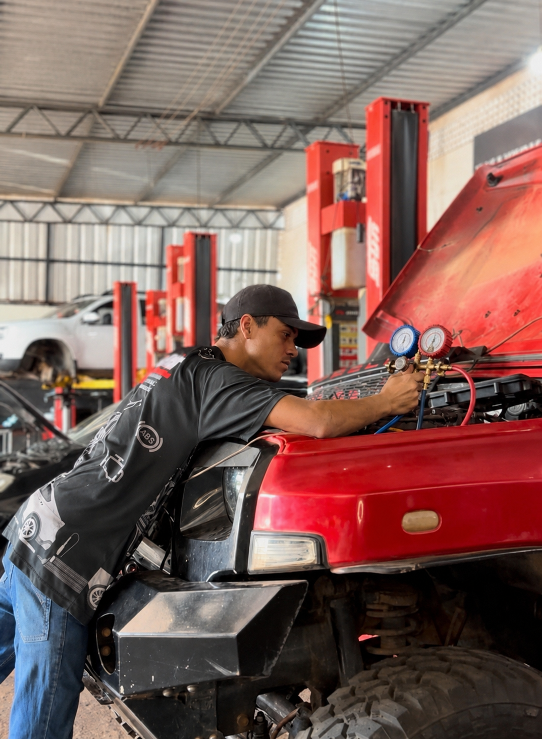 Mecânico da Adenir realizando manutenção do ar-condicionado de um veículo